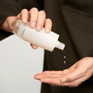 Absolute Silk Micro Essence in Lotion wird aus der Flasche in die Hand des Models gegossen